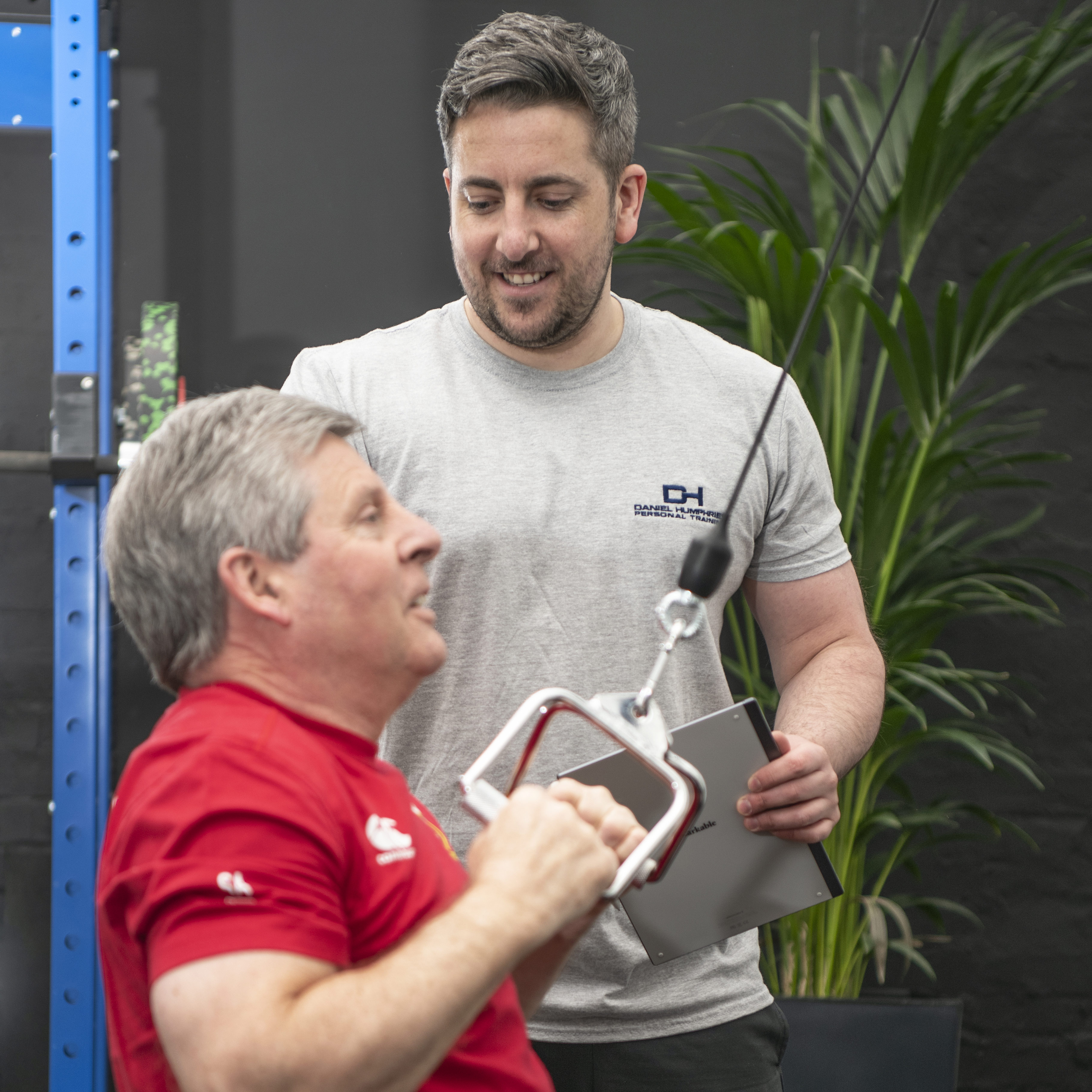 PT Club coach guiding a client through a cable machine exercise
